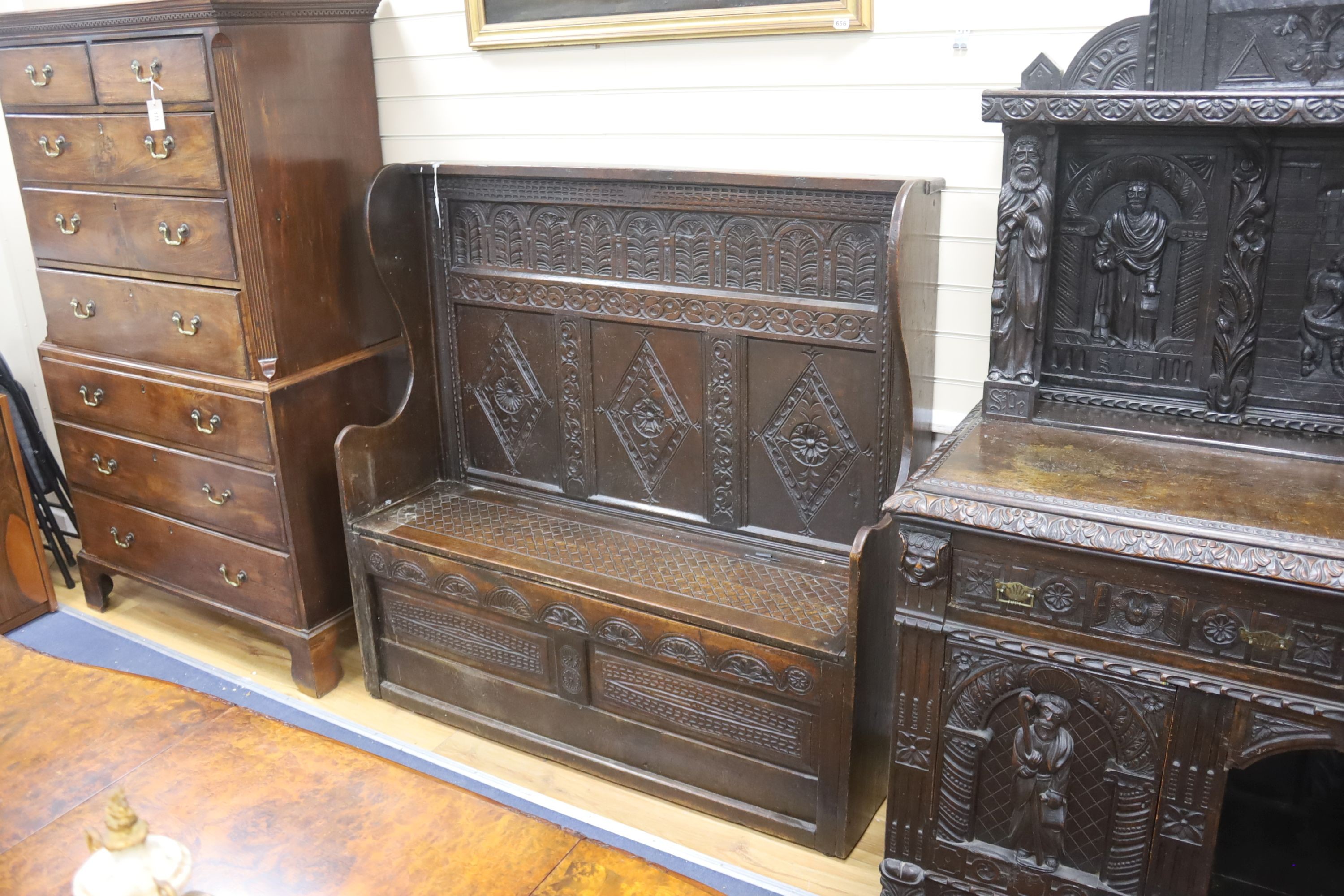 An 18th century and later carved oak settle with hinged box seat, width 137, depth 42, height 137 cms.